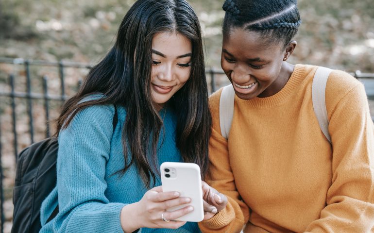 two women laughing at funny memes on phone