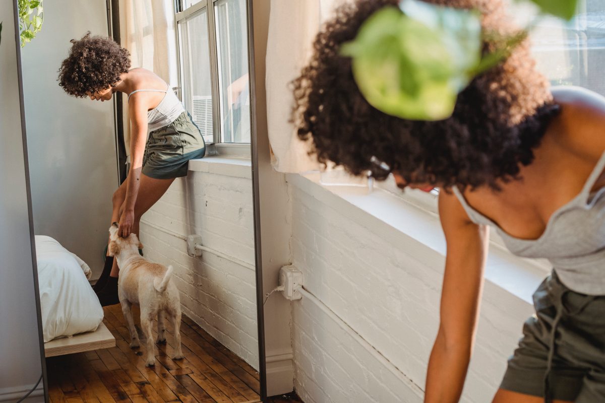 woman petting dog in front of a mirror