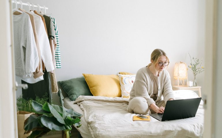 woman on laptop in small bedroom
