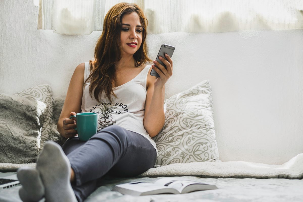 woman holding cup and looking at hbo max on phone