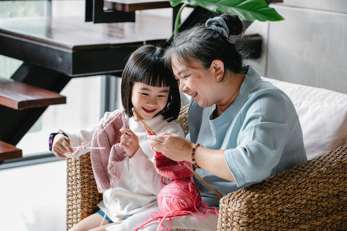Smiling child and grandmother knitting together
