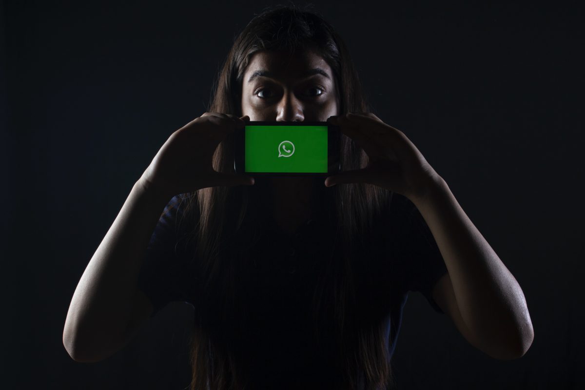 woman holding phone with whatsapp site logo on screen