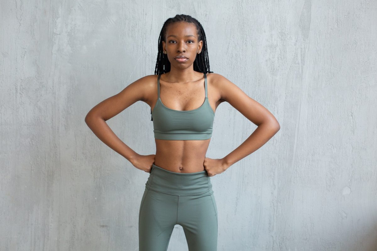 Photo of a fit woman wearing a set of teal gym clothes as she poses with her hands on her hips.