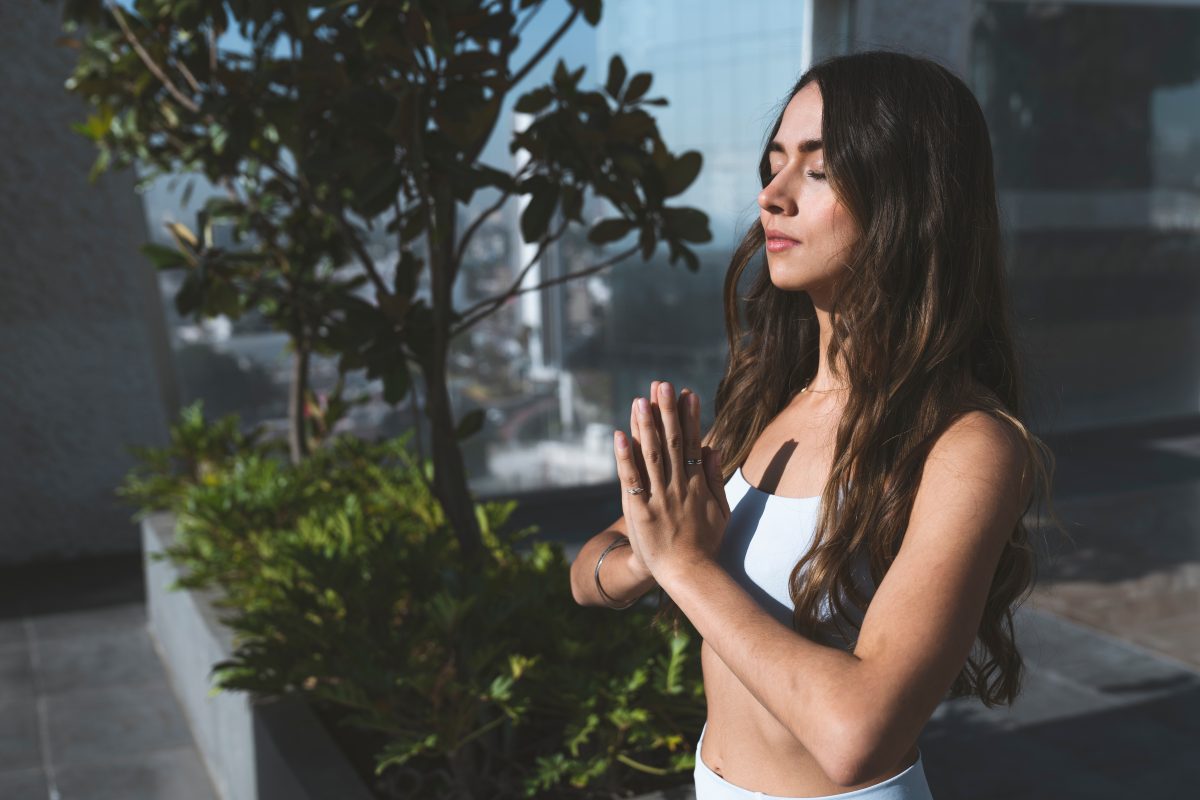 Serene looking woman meditating on a rooftop garden, one of the ways on how to glow up mentally and emotionally. 