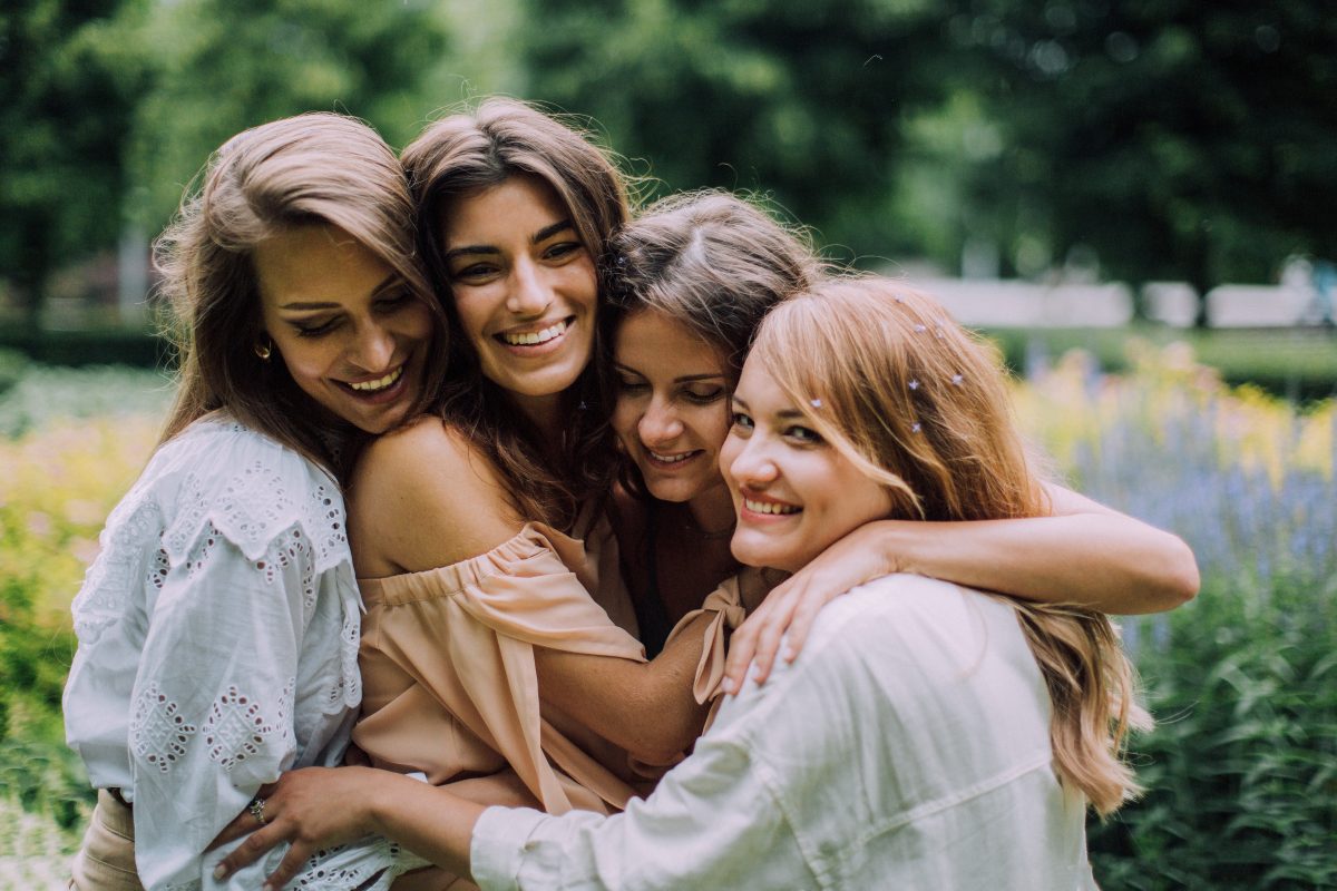 Four friends hugging each other and smiling. 