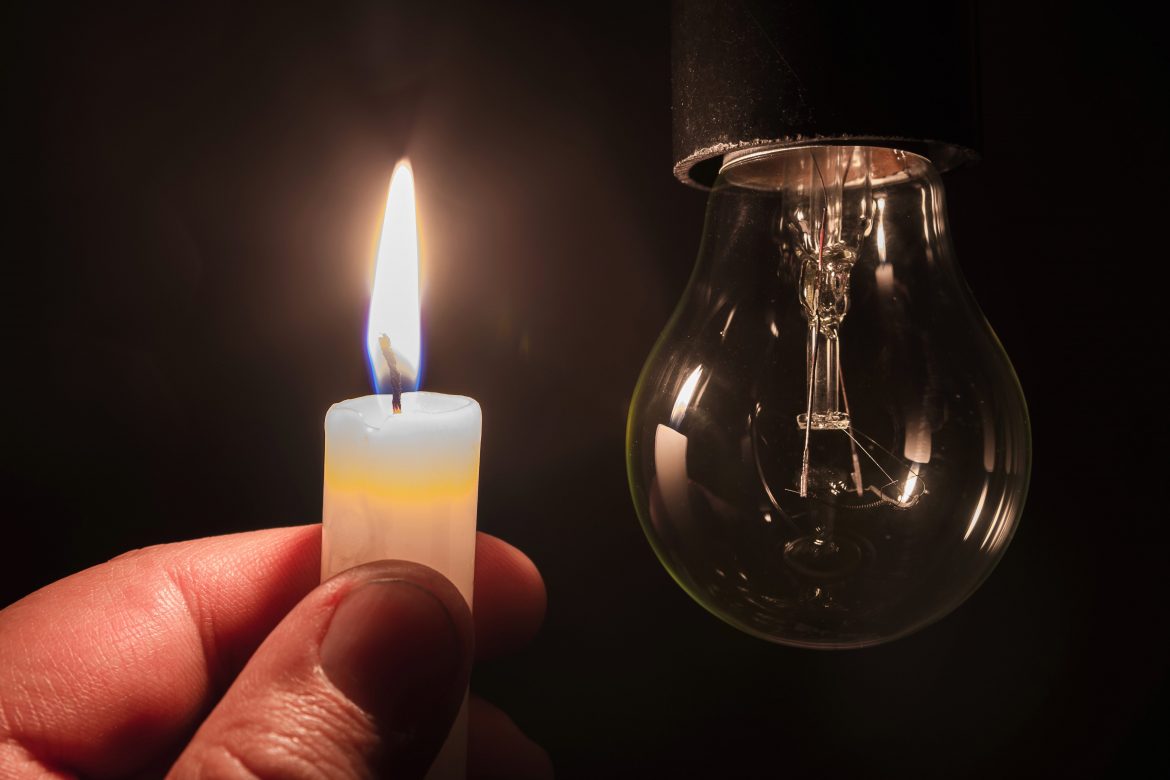 Burning candle near a switched off light bulb