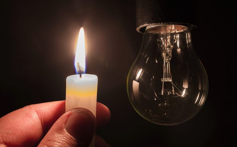 Burning candle near a switched off light bulb