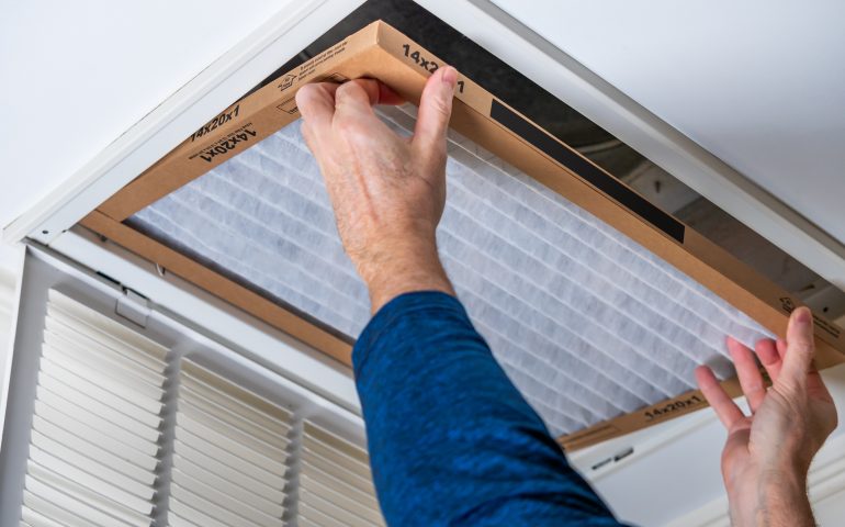 Man replacing dirty HVAC air filter in ceiling vent