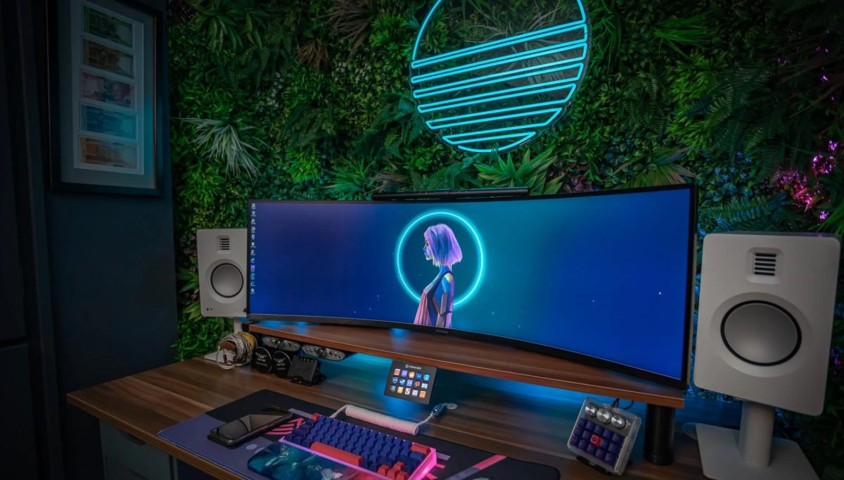 Gaming setup with neon lights and an artificial green wall.