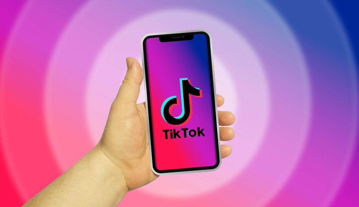 hand holding a mobile phone that shows the Tiktok logo