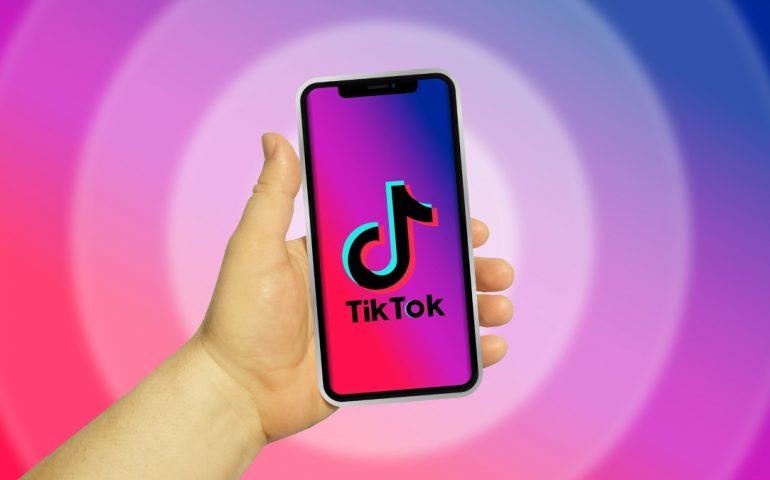 hand holding a mobile phone that shows the Tiktok logo