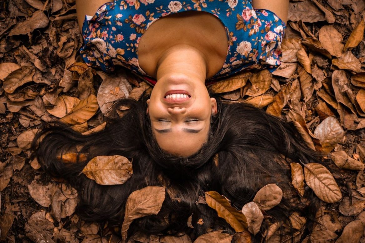 woman with dark brown hair lying on a bed of autumn leaves