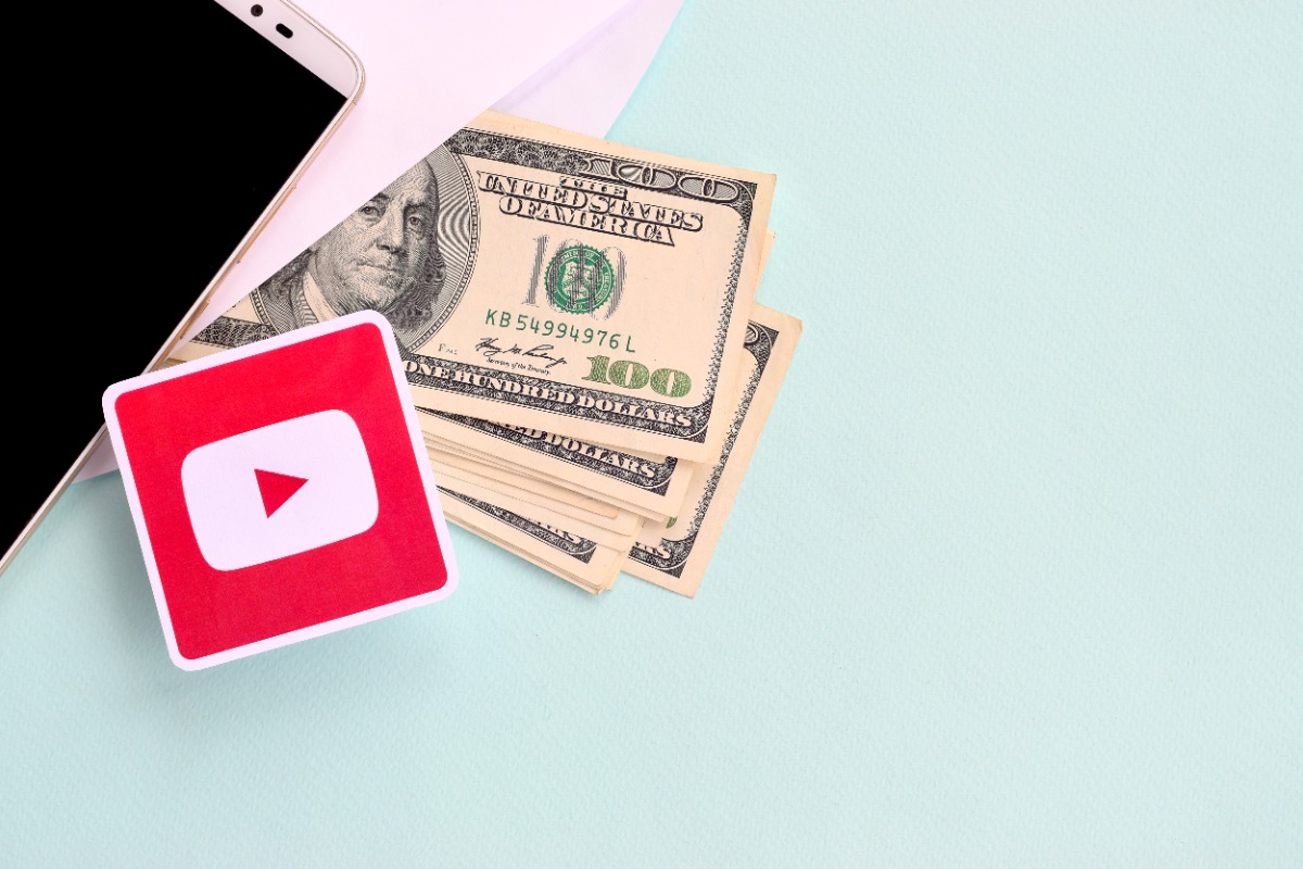 Youtube paper logo lies with envelope full of dollar bills and smartphone